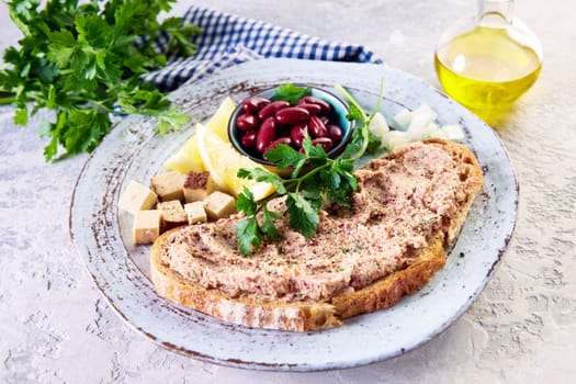 From above of delicious bruschetta with vegetarian pate served on plate with bowl of red beans cubed cheese and lemon on table near carafe of olive oil