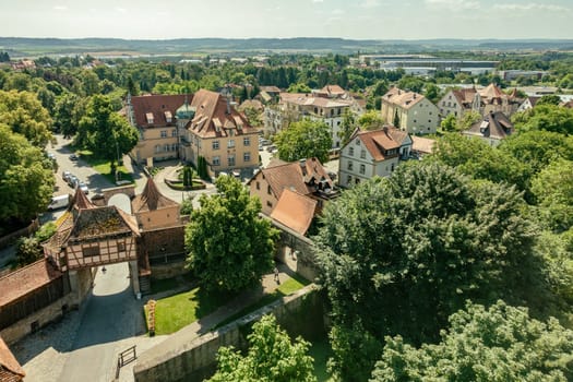 Drone view of residential houses located among tall lush green trees on sunny summer day in Rothenburg ob der Tauber town
