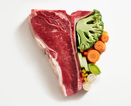 Half tbone steak on white background with carrots, cucumber, broccoli symbolic to eat more vegetables