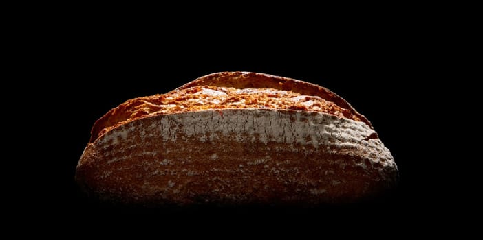 Whole loaf of tasty freshly baked farmers bread with crust covered with flour placed on black background in dark studio