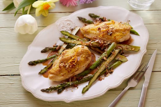 High angle of palatable chicken with fresh asparagus served with sauce on plate on table for Easter celebration in spring