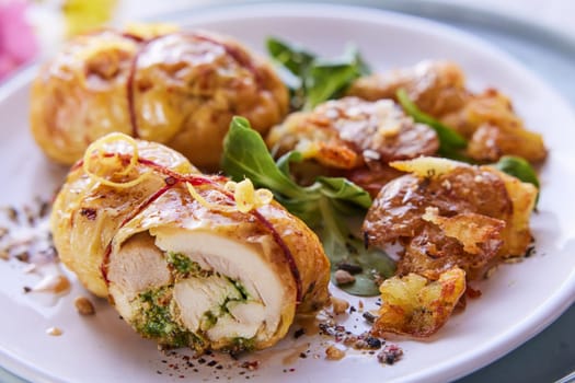 High angle of palatable filled chicken thighs with fresh greenery served on plate on table for lunch