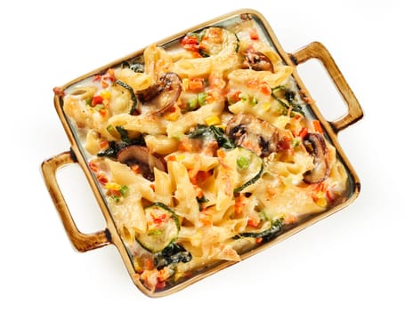Top view of palatable baked penne gratin with champignons and vegetables serve in casserole on white isolated background