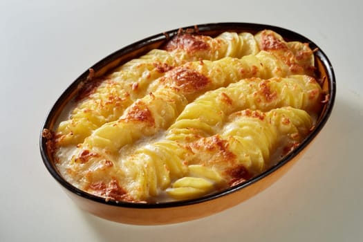 From above of casserole pan with appetizing traditional gratin au potato with cheese served on white table in kitchen