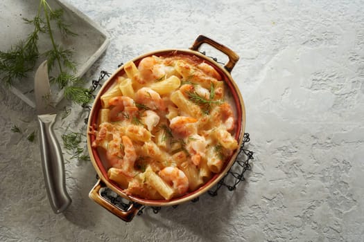From above of delicious homemade creamy pasta with seafood and cheese served on gray table near sharp knife and dill branch in kitchen