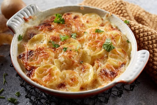 High angle of appetizing homemade potato casserole topped with browned crust made of grated cheese on metal stand near towel