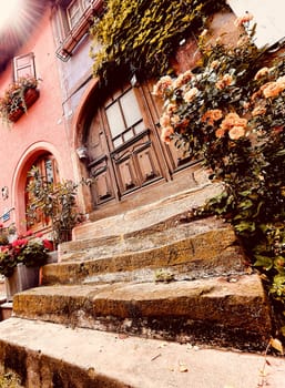 From below of vintage building with aged wide stone porch decorated with fresh flower bunches in Provence on sunny day