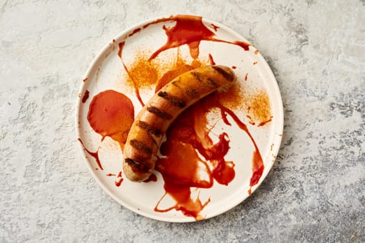 Top view of currywurst German fast food dish with smeared ketchup and curry on ceramic plate