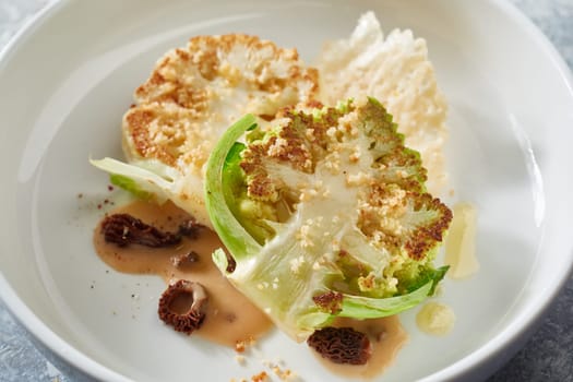 High angle of tasty vegetarian cauliflower steaks with sauce served in fine dish style