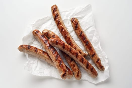 From above of delicious grilled sausages placed on paper napkin against while background in studio