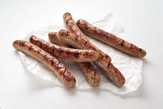 From above of delicious sausages placed on crumpled paper napkin against white background