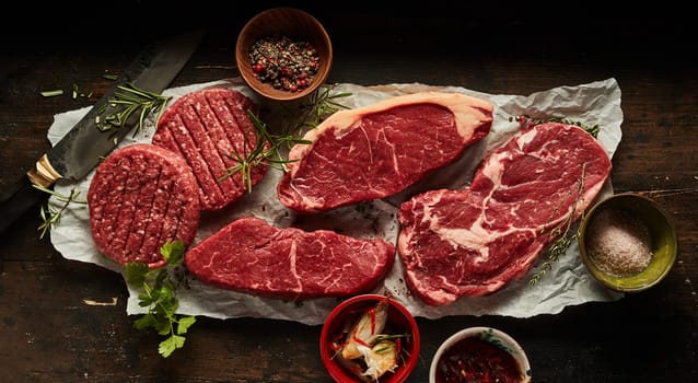 Overhead composition of assorted raw beef ribeye and sirloin steaks with cutlets placed on crumbled paper