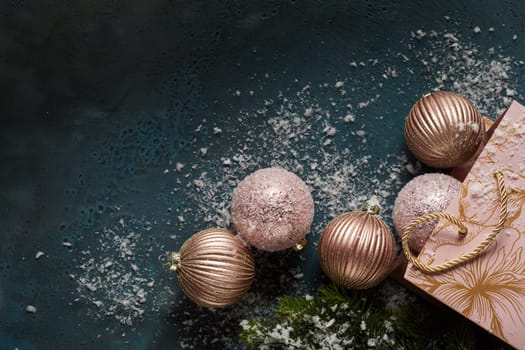 Top view of Christmas baubles and gift bag placed on black table with artificial snow