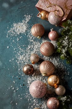 Top view of various shimmering Christmas balls and gift bag placed on artificial snow on black background