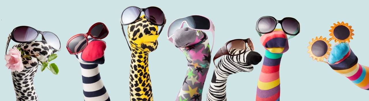 Colorful creative socks in various trendy sunglasses in puppet show on blue background