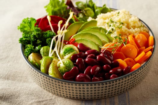 High angle of appetizing various vegetables and couscous in bowl placed for lunch on table with linen tablecloth