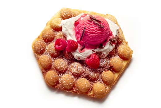 From above of appetizing bubble wafer with pink ice cream scoop and ripe raspberries placed on white isolated background