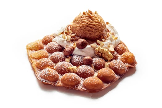 High angle of appetizing egg wafer with chocolate ice cream ball and assorted nuts served on white table in studio