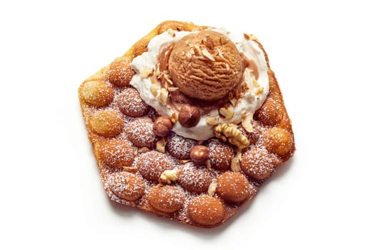 From above of delicious sweet bubble wafer with chocolate ice cream ball and nuts served on white background in studio