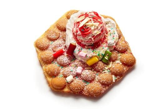 High angle of delicious egg wafer with ice cream ball and gummy candies served on white background in studio