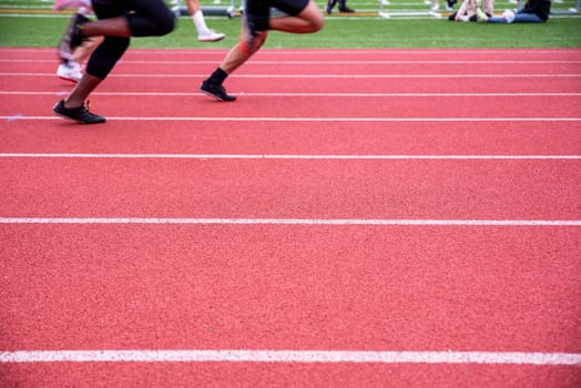 Two runners compete side by side racing on an outdoor sports track with fresh white lane markings in natural light with copy space.
