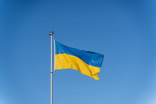 Ukrainian flag of yellow-blue colors on the background of clear blue sky.