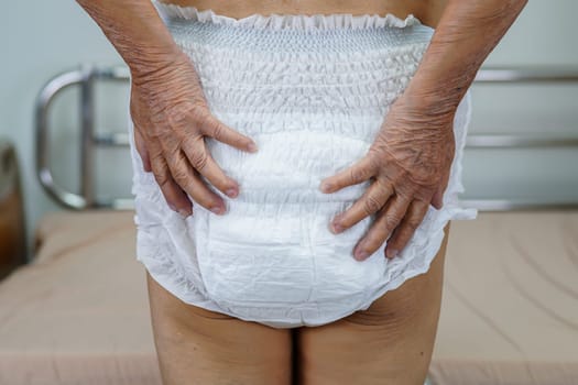 Asian elder senior woman patient wearing adult incontinence diaper pad in hospital.