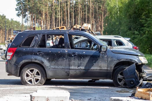Shot car during the war in Ukraine. A car of civilians with shrapnel holes from explosions. Traces of shots on the body. The car was damaged after the shelling. Ukraine, Irpen - May 12, 2022