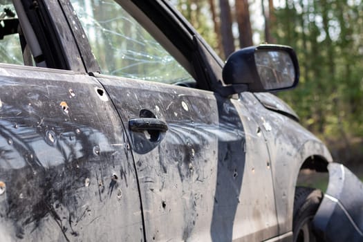 A car of civilians shot by the invaders during the war in Ukraine. Road accident or incident, car accident. Shrapnel holes in the body of the car. Atrocities of the Russian army