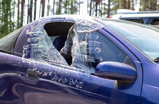 Criminal incident. Breaking into a car parked on the street. Broken side glass and the passenger compartment behind it. A crime committed by a thief, stealing things. Car after an accident