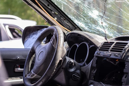 Shot car during the war in Ukraine. A car of civilians with shrapnel holes from explosions. Car accident. Car graveyard. Traces of shots on the body. The vehicle was damaged after the shelling