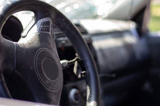 Close-up of the steering wheel of a car after an accident. The driver's airbags did not deploy. Soft focus. Broken windshield with steering wheel. Vehicle interior. Black dashboard and steering wheel