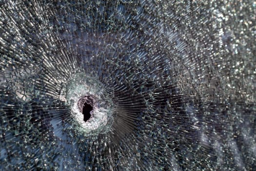 Holes on the windshield of the car, it was shot from a firearm. Bullet holes. Smash car windshield, broken and damaged car. The bullet made a cracked hole in the glass