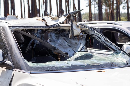 Shot car during the war in Ukraine. A car of civilians with shrapnel holes from explosions. Car accident. Car graveyard. Traces of shots on the body. The vehicle was damaged after the shelling