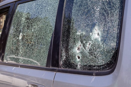 Traces of shots on the body of the car. War between Russia and Ukraine. Part of a civilian car that was fired upon during the evacuation of unarmed people from the combat zone