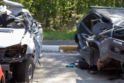 Many broken cars after a traffic accident in the parking lot of a restoration service station on the street. Car body damage workshop outdoors. Sale of insurance emergency vehicles at auction