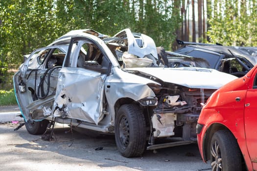 Many broken cars after a traffic accident in the parking lot of a restoration service station on the street. Car body damage workshop outdoors. Sale of insurance emergency vehicles at auction