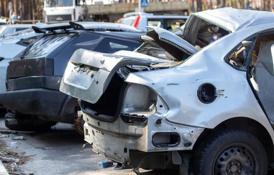 Many broken cars after a traffic accident in the parking lot of a restoration service station on the street. Car body damage workshop outdoors. Sale of insurance emergency vehicles at auction