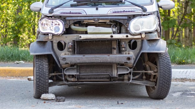 A broken small car after a traffic accident in the parking lot of a repair station on the street. Car body damage workshop outdoors. Sale of insurance cars at auction. Ukraine, Irpen - May 12, 2022