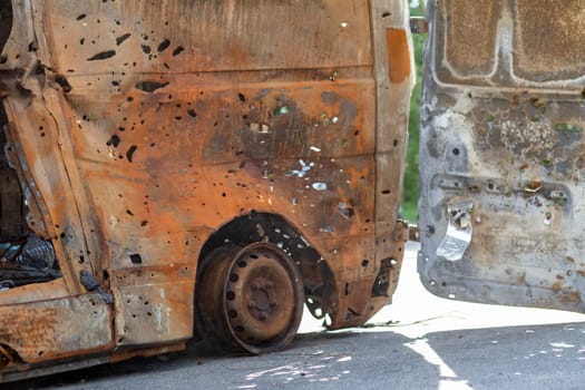 Burnt car body riddled with bullets. Russia's war against Ukraine. Shot by the Russian military car of civilians during the evacuation. Traces of bullets and fragments of shells