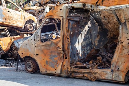 Cars after the fire. Iron parts of a burnt car. Burnt-out cars abandoned on the side of a quiet countryside. Explosion, the result of a fire. Car insurance concept. War of Russia against Ukraine
