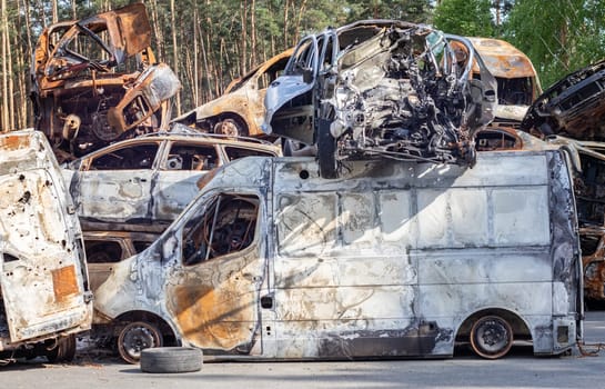 Cars after the fire. Iron parts of a burnt car. Burnt-out cars abandoned on the side of a quiet countryside. Explosion, the result of a fire. Car insurance concept. War of Russia against Ukraine