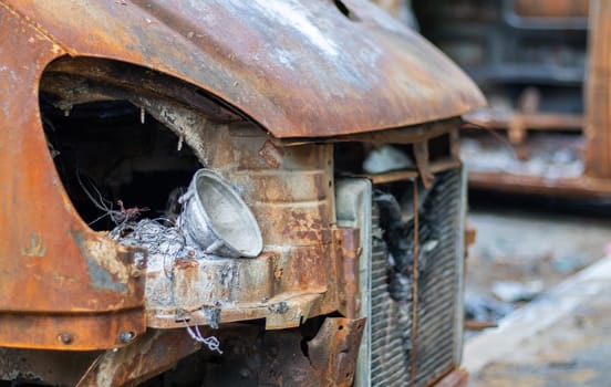 The car was completely destroyed by fire. Abandoned, burnt and rusty car by the road. Cars were on fire in the parking lot. War of Russia against Ukraine. Shrapnel and bullet holes in cars