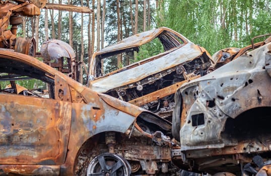 A view of burnt-out cars after rocket attacks by the Russian military. War of Russia against Ukraine. Civil vehicle after the fire. Cemetery of cars in the city of Irpin. Rusty pile of metal