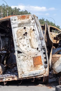 Cars after the fire. Iron parts of a burnt car. Burnt-out cars abandoned on the side of a quiet countryside. Explosion, the result of a fire. Car insurance concept. War of Russia against Ukraine