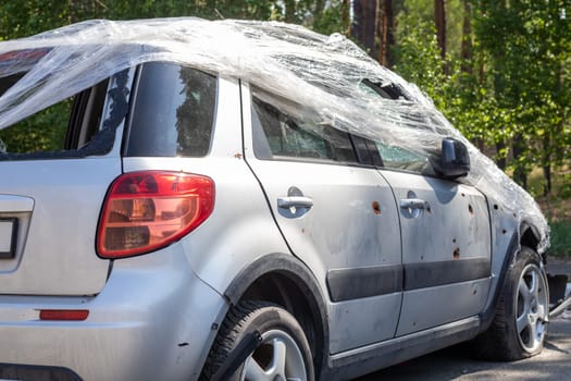 Shot, damaged cars during the war in Ukraine. The vehicle of civilians affected by the hands of the Russian military. Shrapnel and bullet holes in the body of the car. War of Russia against Ukraine