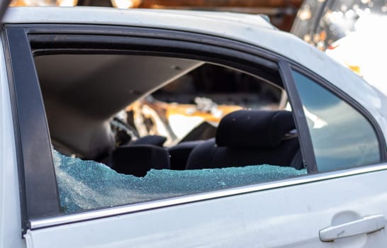 Criminal incident. Breaking into a car parked on the street. Broken side glass and the passenger compartment behind it. A crime committed by a thief, stealing things. Car after an accident