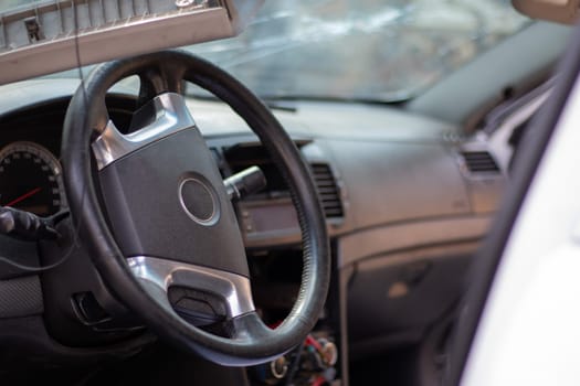 Close-up of the steering wheel of a car after an accident. The driver's airbags did not deploy. Soft focus. Broken windshield with steering wheel. Vehicle interior. Black dashboard and steering wheel