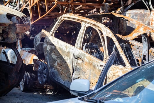 The car burned down completely, even the tires burned out. Burnt out car crash after fire. The bomb shell of the terrorist attack blew up civilians. Disaster zone. Abandoned car on the road