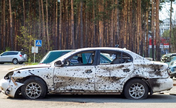 Shot, damaged cars during the war in Ukraine. The vehicle of civilians affected by the hands of the Russian military. Shrapnel and bullet holes in the body of the car. War of Russia against Ukraine
